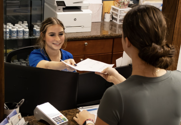 A young employee takes a paper form from a young woman.