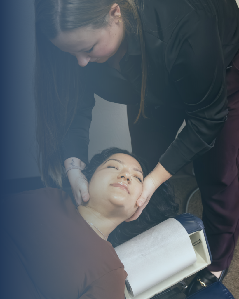 A chiropractor performs a gentle neck adjustment for a young patient laying down on the treatment table.