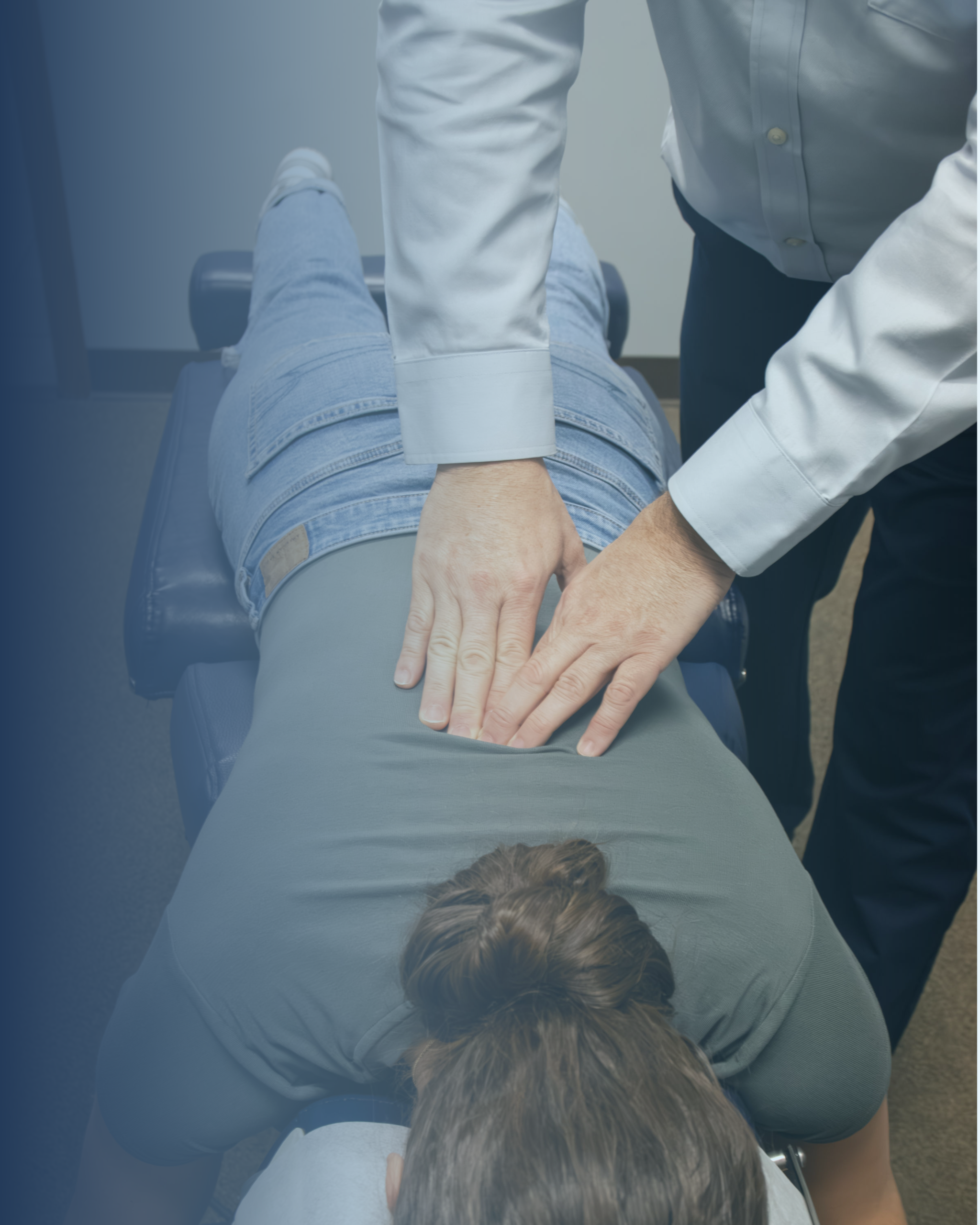 A young female patient lies down while a doctor massages and presses on her low back.